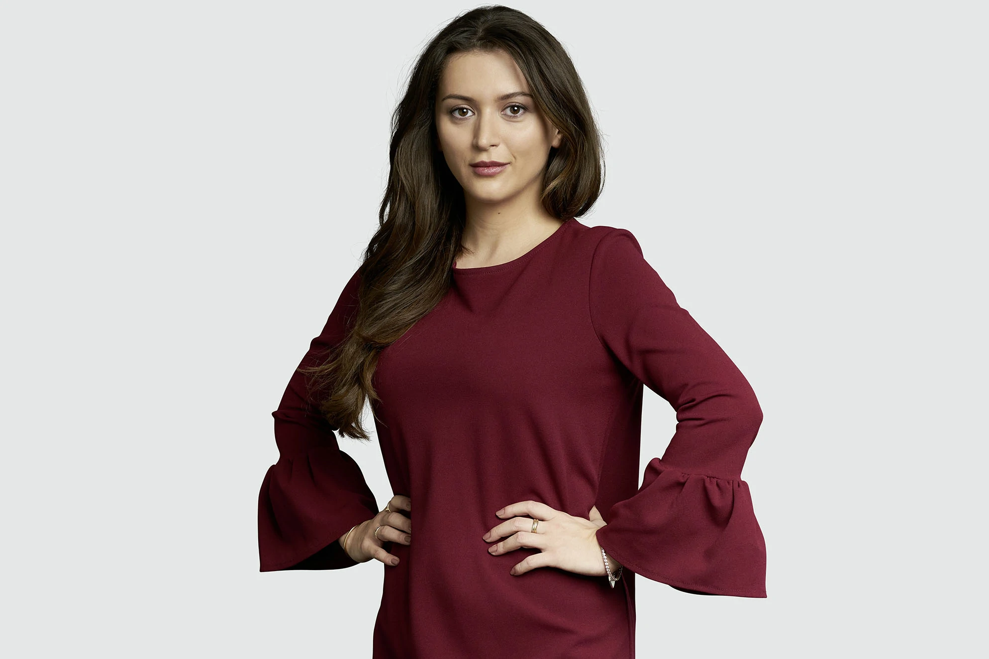 A woman wearing a red top with bell sleeves.